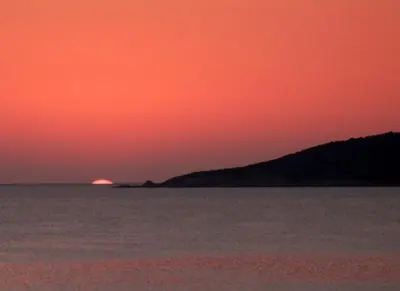 a sunset over the water with the sun in the distance at L'armandulina in Sagone