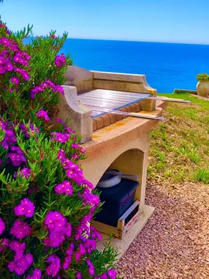 a bench sitting on the beach with purple flowers at L'armandulina in Sagone