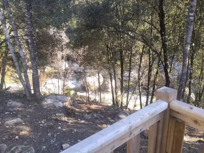 a wooden fence in a wooded area with trees at Camping Les Eaux Vives in Vero