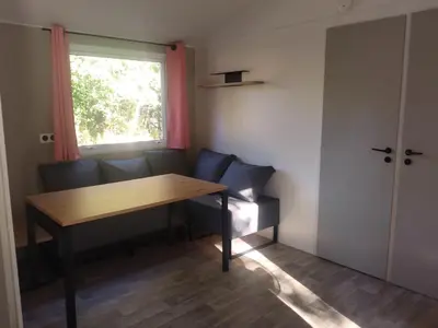 a room with a table and a couch and a window at Camping Les Eaux Vives in Vero