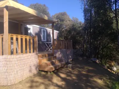 a house with a porch and a gate and a fence at Camping Les Eaux Vives in Vero