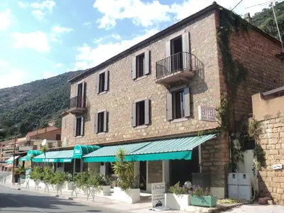 a large brick building with a balcony on a street at Hotel & Restaurant Le Beau Sejour in Porto Ota