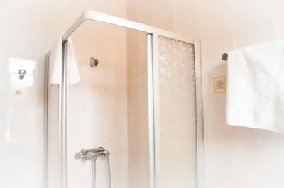 a shower with a glass door in a bathroom at Hotel & Restaurant Le Beau Sejour in Porto Ota