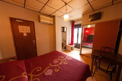 a bedroom with a red bed and a living room at Hotel & Restaurant Le Beau Sejour in Porto Ota