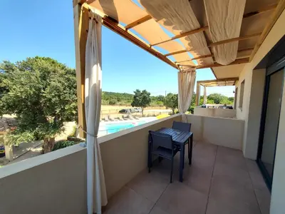 a balcony with a table and a view of a pool at Villas Lantana in Porto-Vecchio