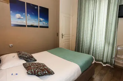 a small bedroom with two beds and a window at Hôtel Duc De Padoue in Corte