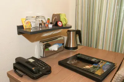 a desk with a phone and a tray on a table at Hôtel Duc De Padoue in Corte
