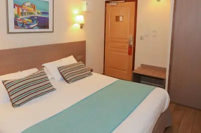 a bedroom with a bed with two pillows on it at Hôtel Duc De Padoue in Corte