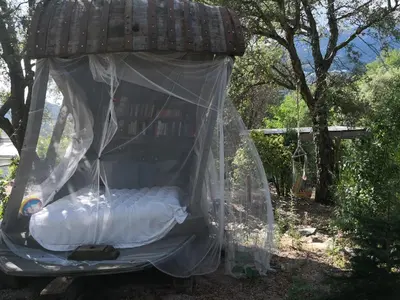 a bed in a canopy in a garden at A Cantina Chalet avec Piscine proche d Ajaccio in Carbuccia