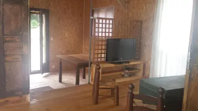 a living room with a tv and a table with a chair at A Cantina Chalet avec Piscine proche d Ajaccio in Carbuccia