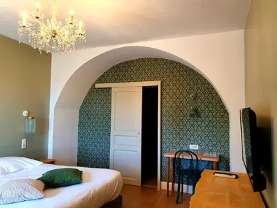 a bedroom with a bed and a table and a chandelier at Hôtel U Frascone in Venaco