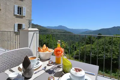a table with food and drinks on a balcony at Hôtel U Frascone in Venaco