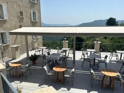 a group of tables and chairs on a patio at Hôtel U Frascone in Venaco