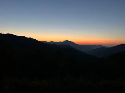 a sunset over a mountain range with the sun setting at Hôtel U Frascone in Venaco