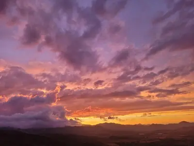 a cloudy sky at sunset with mountains in the background at Conca d'Oro in Vallecalle