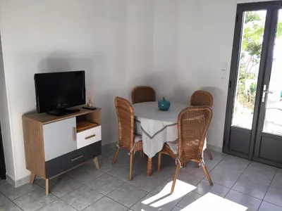 a dining room with a table and chairs and a television at Gites Ugliastru PORTICCIO in Eccica-Suarella