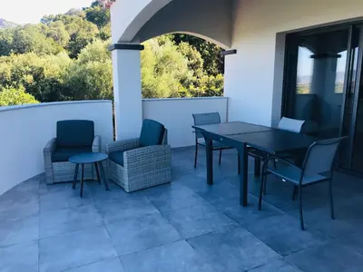 a patio with a table and chairs on a balcony at Gites Ugliastru PORTICCIO in Eccica-Suarella