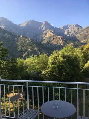 a table and a chair on a balcony with mountains at 1er Consul SAS a Bussinca in Bocognano