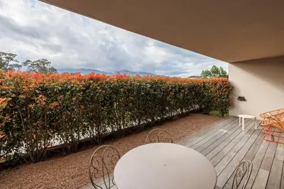 a patio with a white table and chairs and a wall of flowers at Le Balamina in Porto-Vecchio