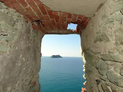 a window in a wall looking out at the ocean at Vue sur mer et montagnes in Moriani Plage