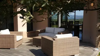 a group of wicker chairs and a couch on a patio at Domaine les Hauts de Capicciola in Pinarellu