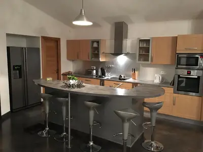 a kitchen with a large island with bar stools at Domaine les Hauts de Capicciola in Pinarellu