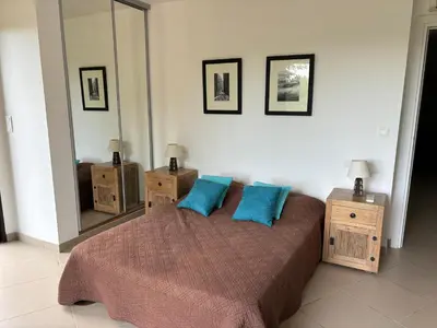 a bedroom with a large bed with blue pillows at Domaine les Hauts de Capicciola in Pinarellu