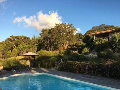 a swimming pool in front of a house at Domaine les Hauts de Capicciola in Pinarellu