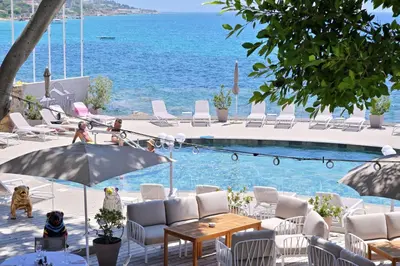 a swimming pool with chairs and a table and an umbrella at Hôtel Restaurant Dolce Vita in Ajaccio