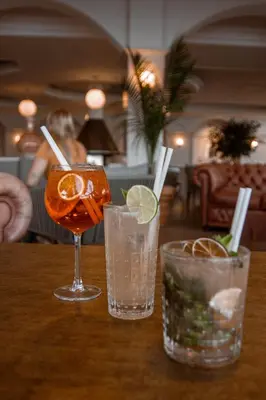 three cocktails sitting on a wooden table at Hôtel Restaurant Dolce Vita in Ajaccio