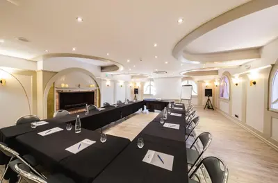 a meeting room with black tables and chairs and a podium at Hôtel Restaurant Dolce Vita in Ajaccio