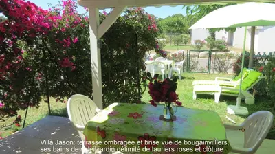 a table and chairs in a yard with pink flowers at Jason in Cervione
