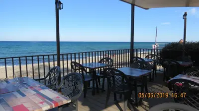 a patio with tables and chairs on the beach at Jason in Cervione
