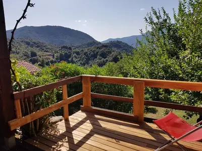 a deck with a chair and a view of mountains at les chalets montagne alta rocca in Zicavo