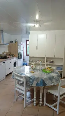 a kitchen with a table and white cabinets at les chalets montagne alta rocca in Zicavo