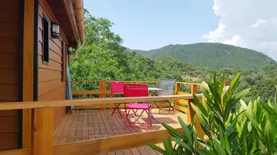 a deck with chairs and a table with a mountain at les chalets montagne alta rocca in Zicavo
