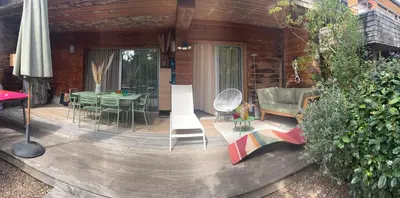 a wooden deck with a table and chairs on it at Residence Cala Sultana -Baie Santa Giulia - rez jardin 1ere ligne in Porto-Vecchio