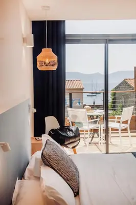 a bedroom with a bed and a balcony with a table and chairs at Auberge Kallisté - Eco Label in Porto Pollo
