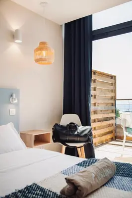 a bedroom with a bed and a chair and a window at Auberge Kallisté - Eco Label in Porto Pollo