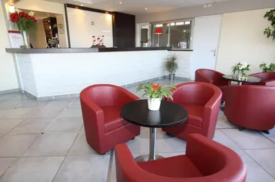a waiting room with red chairs and a table at Les Roches Blanches in Porto-Vecchio