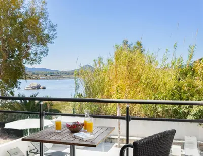 a table on a balcony with a view of a river at Les Roches Blanches in Porto-Vecchio