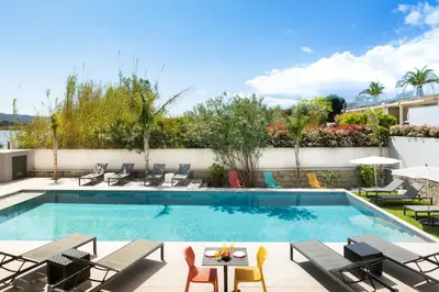 a swimming pool with chairs and a table next to a building at Les Roches Blanches in Porto-Vecchio