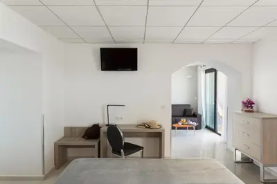a bedroom with a bed and a desk and a tv at Les Roches Blanches in Porto-Vecchio