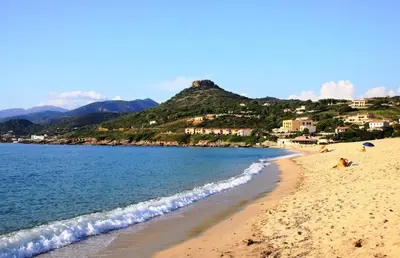 a beach with people laying on the sand and the water at Residence Sejoina in Calcatoggio