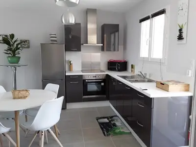 a kitchen with black cabinets and a table with white chairs at Residence Sejoina in Calcatoggio