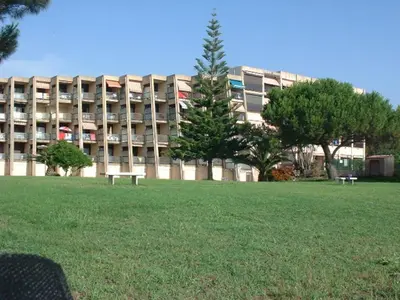 a large building with a park in front of it at Studio les pieds dans l'eau in Santa-Lucia-di-Moriani