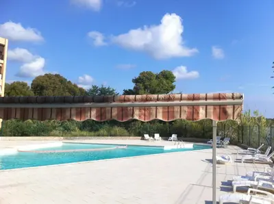 a swimming pool with a table and chairs next to it at Studio les pieds dans l'eau in Santa-Lucia-di-Moriani