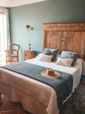a bedroom with a large bed with a hat on it at Hotel La Terrasse in Zonza