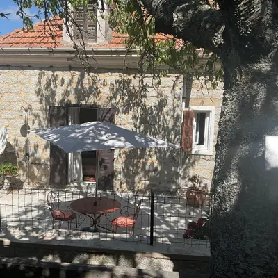 a table and chairs with an umbrella in front of a building at Hotel La Terrasse in Zonza