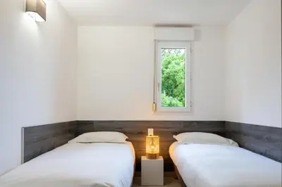 two beds in a room with a window at Résidence Marina Bianca in Santa-Lucia-di-Moriani